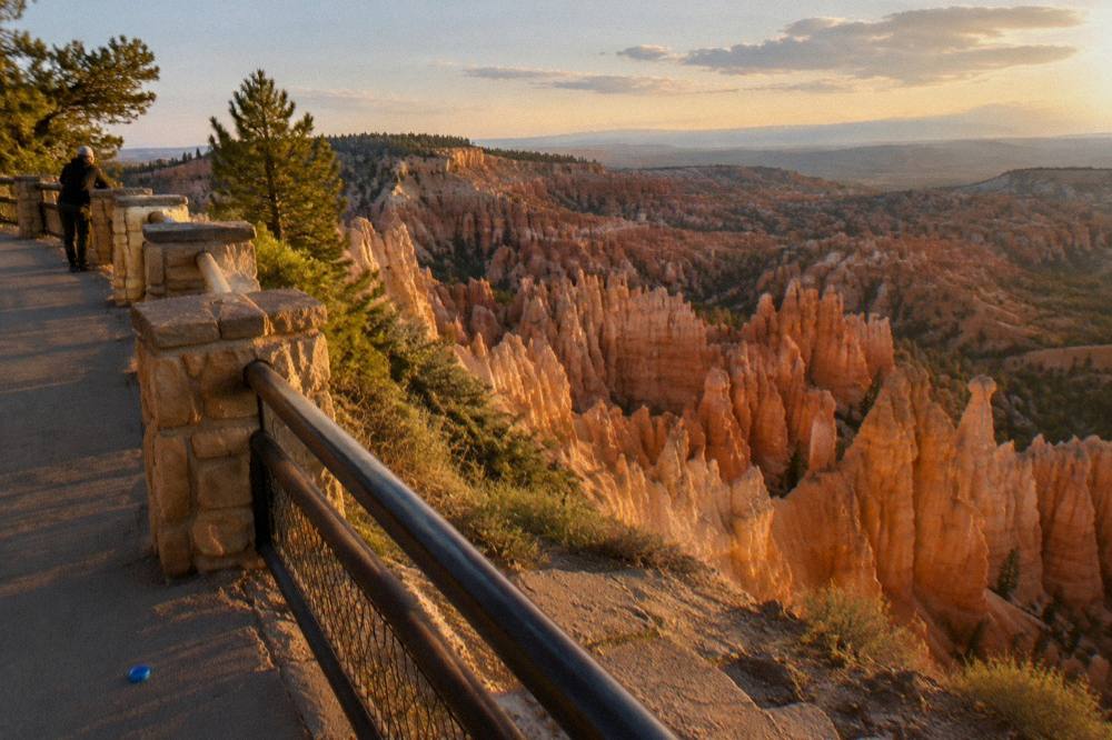 Golden evening light on layered rock spires above a wide canyon viewpoint
